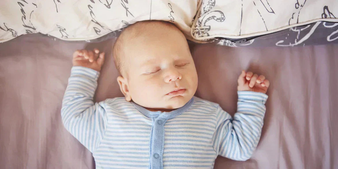 Baby schläft mit Händen neben dem Kopf