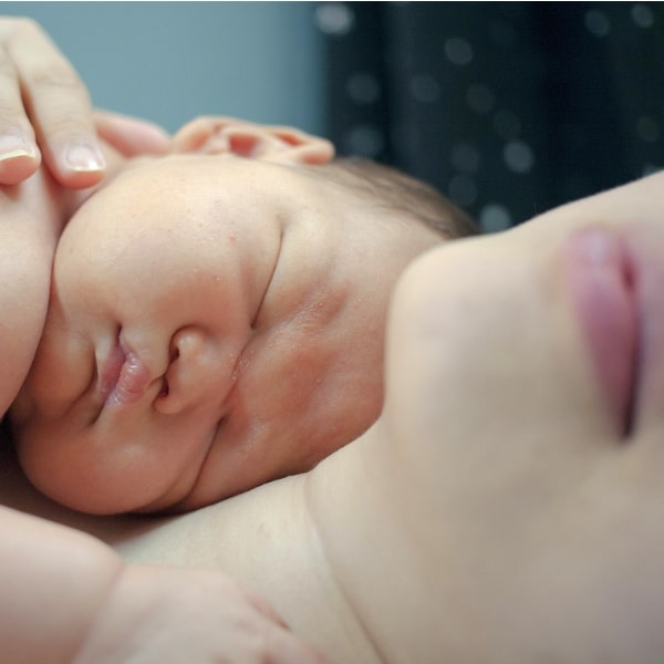 Mama praktiziert Känguru Methode Baby liegt auf Mamas Brust